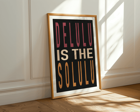 Framed poster with 'DELULU IS THE SOLULU' text on a wall with sunlight casting shadows.