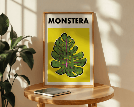 Framed artwork with a monstera leaf design on a wooden table