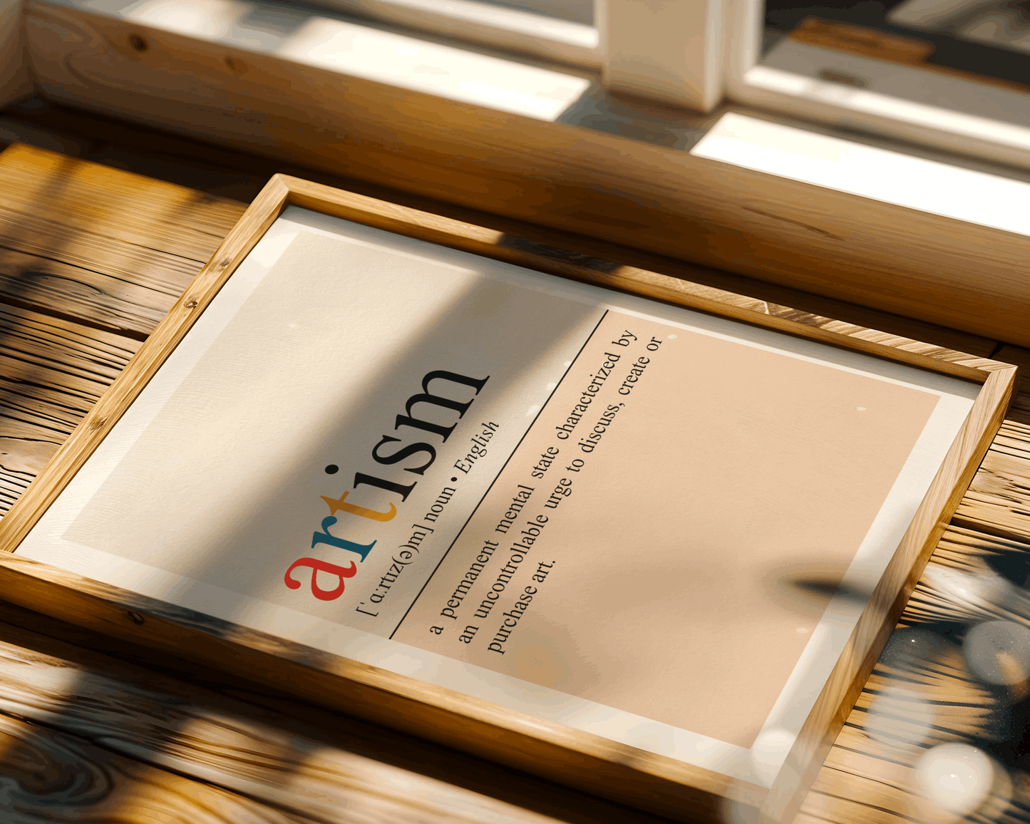Framed dictionary definition of 'artism' on a wooden surface with natural light.