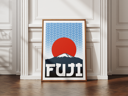 Framed artwork of Mount Fuji with a red sun and blue sky on a white wall.