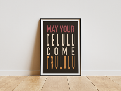 Framed poster with text 'May your DELULU come TRULULU' on a white wall.