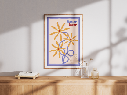 Framed artwork with floral design and text 'Flower lover' on a wall above a wooden surface.