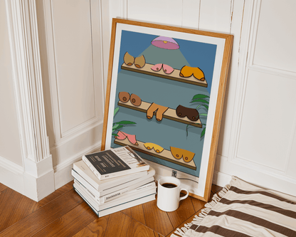Framed artwork of boobs on shelves with books and a mug on a wooden floor.