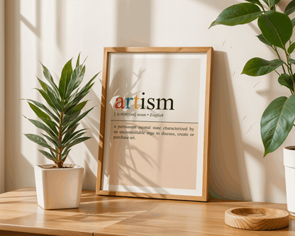 Framed artwork with the word 'artism' displayed on a wooden surface with plants.