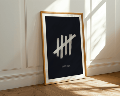 Framed poster with white tally marks on a dark background, leaning against a wall.