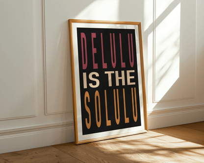 Framed poster with 'DELULU IS THE SOLULU' text on a wall with sunlight casting shadows.