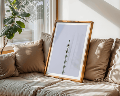 Framed cross-country skiing artwork on a beige sofa with cushions and a plant in the background
