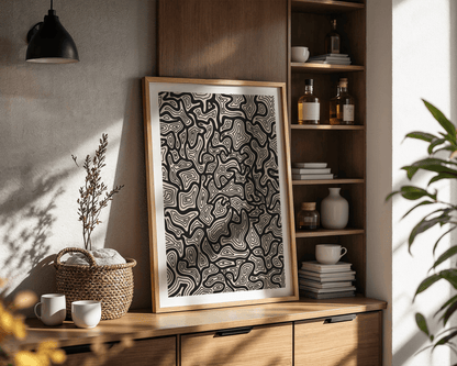 Framed abstract topography artwork on a wooden shelf with decorative items