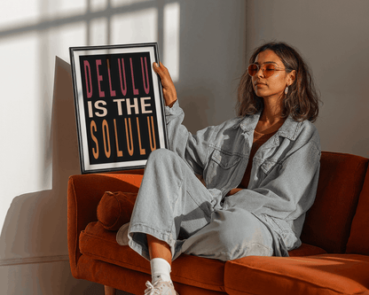 Woman holding a framed picture with text sitting on an orange couch.