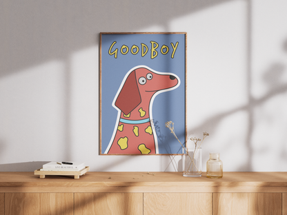 Framed poster of a cartoon dog with 'Good Boy' text on a wall above a wooden surface.