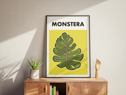 Framed artwork with a monstera leaf design on a wall above a wooden cabinet.