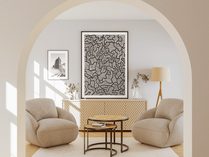 Modern living room with beige armchairs, a side table, and minimalist, modern wall art.