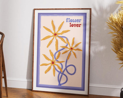 Floral artwork with FLOWER LOVER text leaning on a white wall.